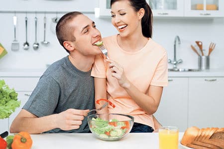 женщина кормит мужчину салатом