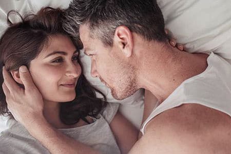 мужчина и женщина смотрят друг на друга лежа в кровати
