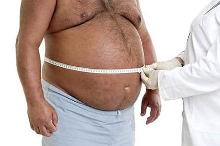 врач измеряет размеры талии полного мужчины