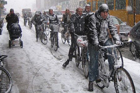 люди едут на велосипедах в снежную погоду